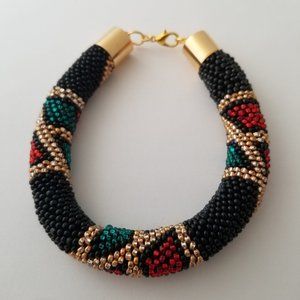 WOMENS HANDMADE SEED BEAD 7 1/2" ETHNIC BRACELET. RED, BLACK, GREEN AND GOLD.